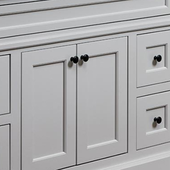 A close up of a light gray painted bathroom vanity with inset cabinet construction.