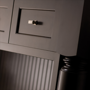 A dark painted kitchen island shows the beautiful, quality details of the cabinets and fine turned post.